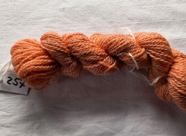 twisted skein of dark salmon pink yarn on a white background