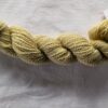 twisted skein of pale olive yarn on a white background.