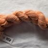 twisted skein of salmon pink yarn on a white background