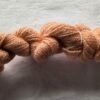 twisted skein of paler salmon pink yarn on a white background