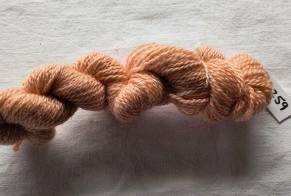 twisted skein of paler salmon pink yarn on a white background