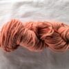 twisted skein of dark salmon pink yarn with some darker red spots