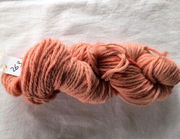 twisted skein of dark salmon pink yarn with some darker red spots