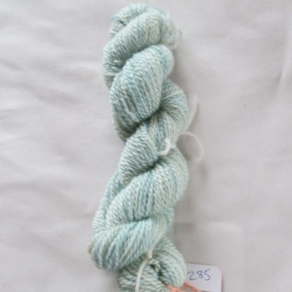 twisted skein of pale blue with paler areas yarn on a white background with a label numbered 285